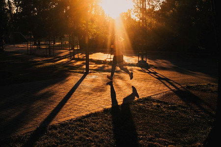 日落时分在公园跑步的人的剪影健康积极的生活方式