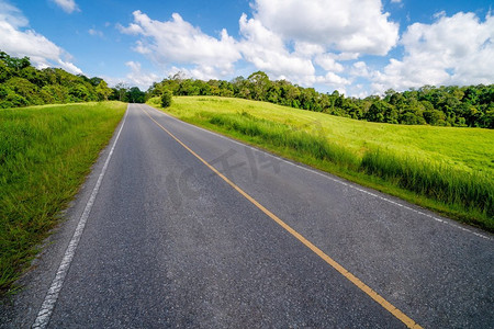 高速公路领域摄影照片_公路上山通过绿色的草地在白云下在蓝天在夏天。公路旅行的概念。