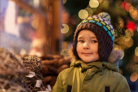 节日、童年和人的概念--冬天的傍晚圣诞集市上的小男孩。冬天圣诞集市上的快乐小男孩