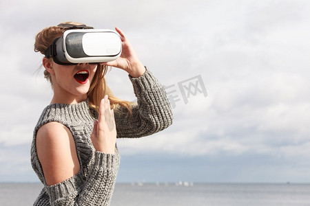 六色打印测试图摄影照片_一名年轻女子在外面测试VR眼镜。女性在春天的天气里戴着虚拟现实耳机。戴着VR的女人在外面