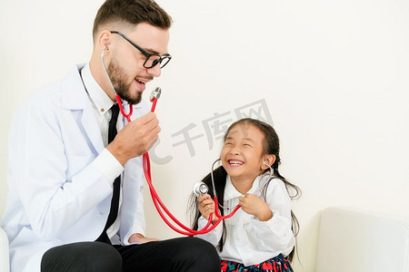 儿童保健宣传栏摄影照片_小孩子到医院的办公室看病。这孩子很开心，也不怕医生。医疗和儿童保健概念。