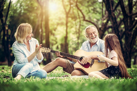 快乐的家庭一起弹吉他和唱歌，而在夏天坐在公园里。音乐中的家庭纽带。