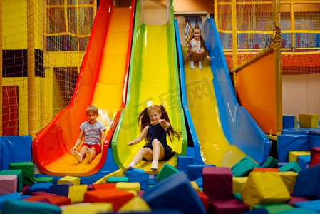 儿童节晚会展板摄影照片_小孩子在娱乐中心的充气滑梯上玩得开心。室内游戏区，游戏室