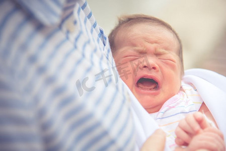 乳腺摄影照片_婴儿在母亲的怀抱中哭泣。新生儿和婴儿健康观念。生日与母亲的爱主题。