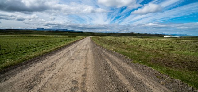 空旷的砾石土路穿过乡村景观和草地。四轮驱动汽车的自然越野旅行。