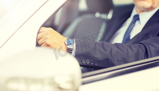 交通、商业、时间和人的概念—高级商人手拿手表驾驶汽车。高级商人手开车