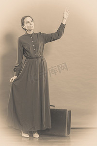 妇女复古风格的长深色礼服与旧行李箱，复古照片深褐色色调