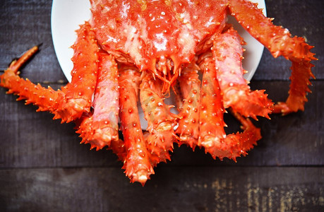 粉色小红书摄影照片_新鲜的阿拉斯加帝王蟹蒸熟或煮熟的海鲜在盘子和木质背景下，俯瞰-北海道红蟹