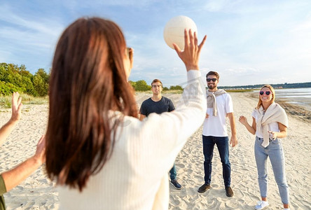 排球，休闲游戏和人的概念-快乐的朋友在夏天在海滩上玩球。夏天在海滩上打排球的朋友