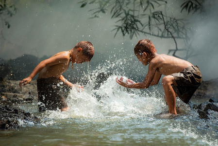 亚洲小朋友在河上/男孩快乐有趣地在小溪里玩水在乡下生活的孩子农民农村人
