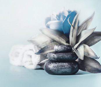 放松的一天。冷静和冷静的概念。一堆有蓝色花朵和毛巾的禅宗石头。健康疗法。SPA设置