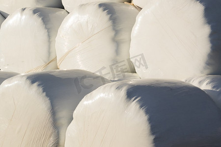 塑料箔纸摄影照片_农业背景从许多稻草包装。用白色塑料箔纸包裹的一捆干草。用塑料箔包裹的干草包