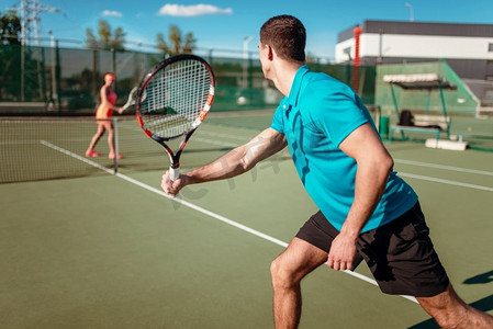 运动会摄影照片_运动男子和苗条女子网球训练在室外球场，球员与球拍。夏季运动会