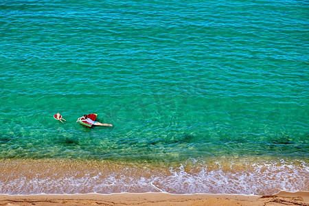 两岁的小男孩和他的母亲在海滩上，带着充气彩车和戒指。暑假全家度假。希腊西索尼亚。