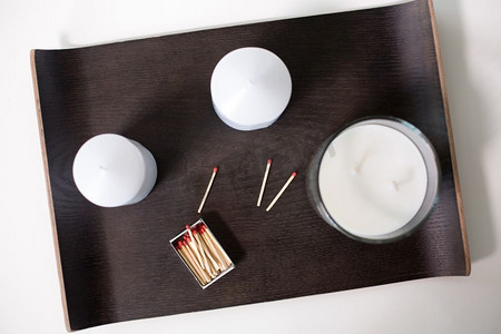路西法摄影照片_装饰，卫生和舒适的概念—白色香味蜡烛和火柴在托盘上的桌子。香味蜡烛和火柴在托盘在桌子上