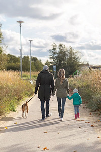 家庭，宠物和人的概念—快乐的母亲，父亲和小女儿散步与比格犬在秋天。快乐的家庭散步狗在秋天