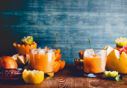 深色墙壁背景摄影照片_橙汁混合在餐桌上的玻璃杯中，在深色墙壁背景下加入各种柑橘类水果成分。维生素C饮料。健康的生活方式。复制空间