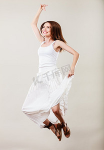 暑假和幸福。穿白色裙子的女人跳。女性模型在全长在灰色背景。