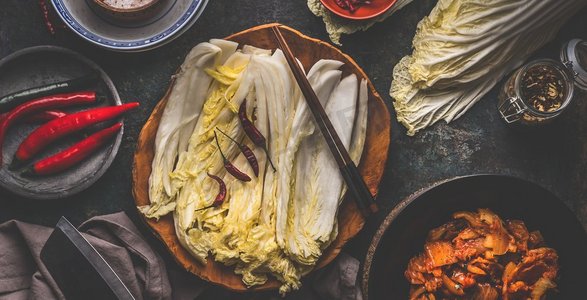 秘制泡菜摄影照片_木碗中的白菜叶，用原料和筷子制作泡菜。俯视图
