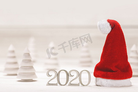 概念性的2020年新年背景与小木冷杉2020年数字和红色圣诞老人帽子。概念2020新年背景