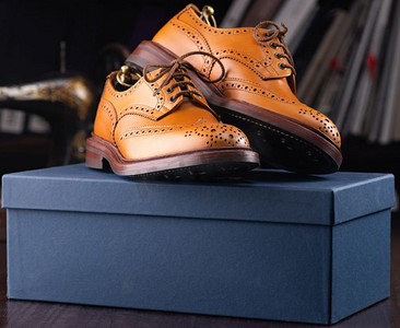 在男鞋精品店陈列的棕色全粒面皮革布鞋上有盒子和布鞋袋..男士鞋类精品店