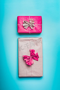 恭喜摄影照片_问候礼物盒在包装纸与弓在蓝色背景，顶视图。平躺。恭喜，节日，生日概念
