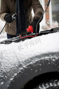 下雪天的车摄影照片_妇女使用跳线电缆上的汽车电池在下雪天