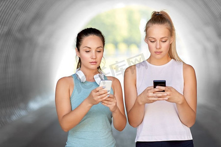 健身，运动和健康的生活方式概念—年轻女性或女性朋友与智能手机。使用智能手机的女性或女性朋友