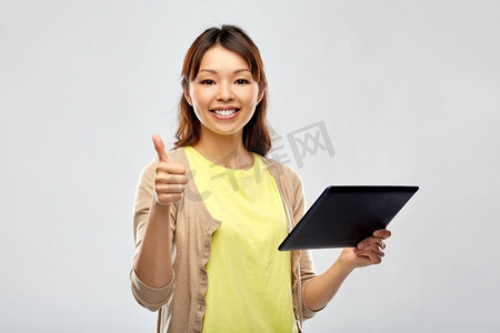 科技与人的概念-快乐的亚洲女性在灰色背景下使用平板电脑。快乐的亚洲女性使用平板电脑
