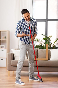 清洁、家务和家政概念-印度男人扫地，在家唱歌。一个男人在家里打扫扫帚，唱歌