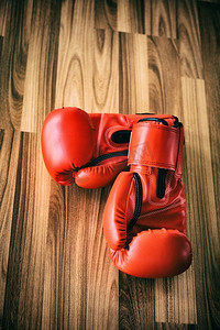 拳头背景摄影照片_红色拳击手套在木背景。运动和健康的生活方式概念。