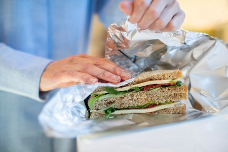 爱不可挡摄影照片_特写妇女包裹三明治在不可重复使用的铝箔