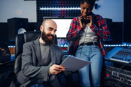 男声音制作人和女歌手戴着耳机在录音室听组成。专业的音频和音乐混音技术