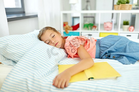 人，童年和休息的概念—小女孩与书睡觉在她的房间在家里。小女孩与书睡在她的房间在家里