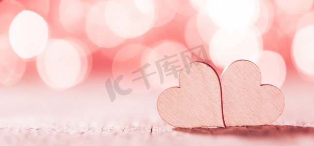 两个手工制作的木心在美丽的粉红色散景背景。复古风格。Love Valentine s Day概念’两颗心在散景背景