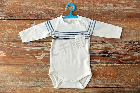 婴儿服装，婴儿期和服装概念-木桌上有衣架的紧身衣。木桌上带衣架的婴儿紧身衣
