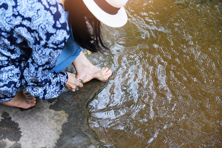 女性水疗中心在自然小溪上用石头清洗脚部/女性洗脚，水疗中心足部按摩