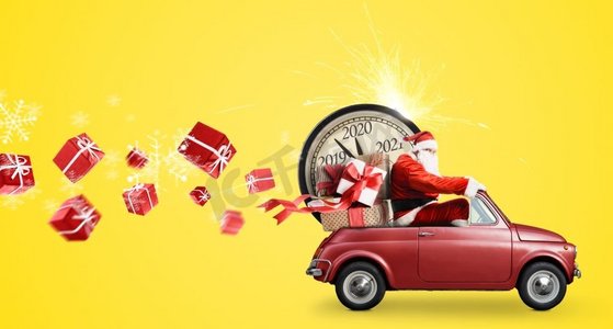 2020圣诞新年摄影照片_圣诞倒计时到了。圣诞老人在雪玩具汽车提供新年礼物和时钟在黄色背景。圣诞老人倒计时车