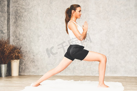 年轻漂亮的女人在家中客厅的地毯上做瑜伽运动。健康的生活方式和放松。