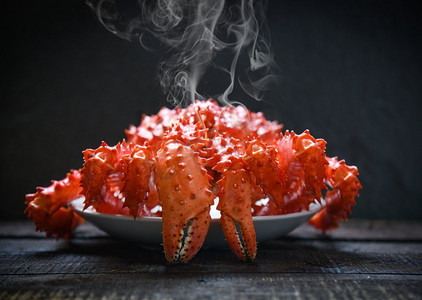 蟹菜摄影照片_红蟹北海道/阿拉斯加帝王蟹熟蒸汽或煮海鲜在黑暗背景