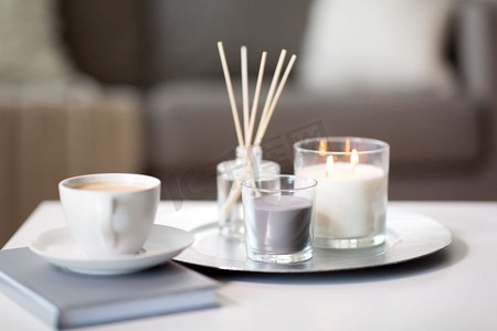 卫生和芳香疗法的概念-咖啡，蜡烛和香草扩散器在家里的桌子上。桌子上有咖啡、蜡烛和香料扩散器