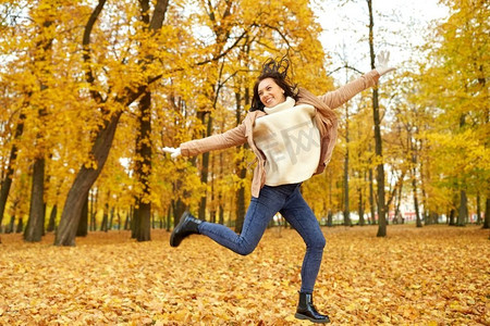 季节和人的概念—快乐的年轻女子在秋天公园。美丽快乐的年轻女子在秋天公园