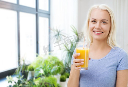 健康饮食，节食和人的概念—微笑的妇女喝橙汁从玻璃在家里。微笑的女人喝橙汁在家里