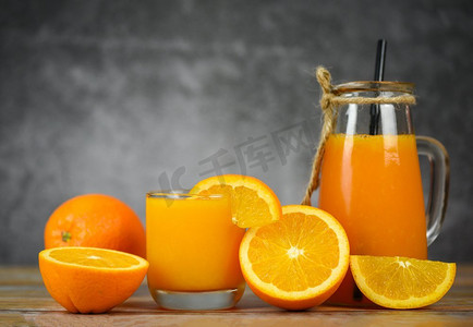 橘子汁在玻璃罐和新鲜的橘子水果片在木桌/静物玻璃汁黑暗与拷贝空间背景