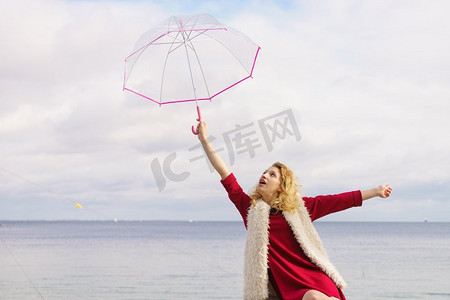 愉快优雅的成年妇女拿着透明伞反对天空。天气预报概念快乐的女人撑伞