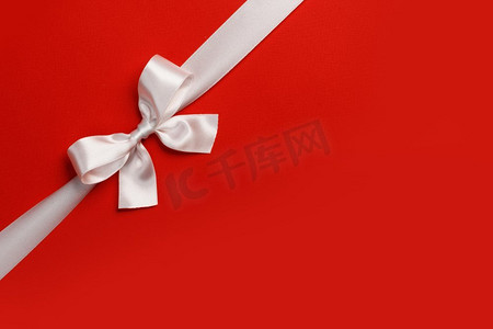 蝴蝶结摄影照片_白色礼物弓在红色背景文本节日礼物概念复制空间。白色礼品蝴蝶结红色