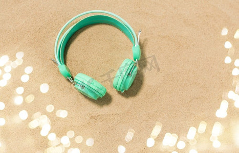 手机夏季夏季摄影照片_音乐、音响设备和度假概念—夏季海滩沙滩上的耳机。夏季沙滩沙滩上的耳机