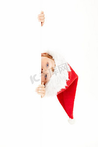开门大吉海报摄影照片_戴着圣诞老人帽子的小男孩看着空白海报，孤立