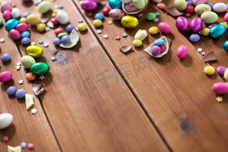 bonbon摄影照片_复活节，糖果和糖果概念—巧克力蛋和糖果滴在木桌子。巧克力蛋和糖果滴在木桌上