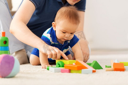 玩玩具的男孩摄影照片_家庭、父亲和童年的概念—男婴和父亲在家里玩玩具积木。男孩与父亲玩玩具块在家里